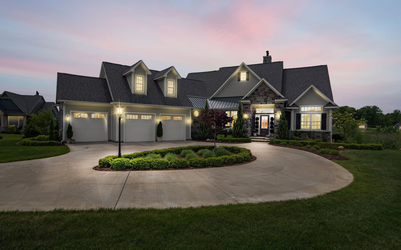 A two-story home with its lights on at dusk